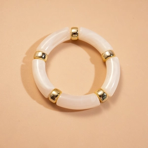 Détail du bracelet en acrylique crème alternant avec des perles en métal doré poli