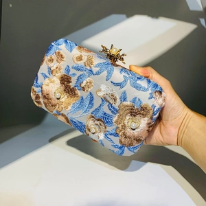 Detail of blue and gold floral embroidery with pearl accents on a vintage evening clutch bag