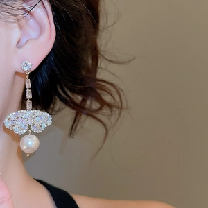 Close-up of model wearing gold drop earrings with butterfly rhinestones and pearls