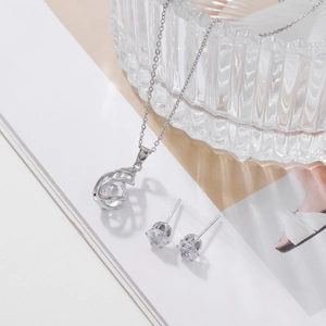 Silver hollow threaded drop necklace and zircon earring set on an elegant background