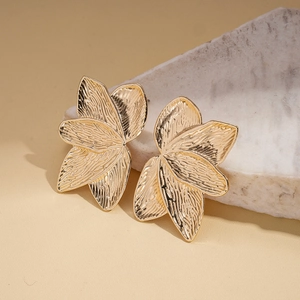 Close-up of golden petal leaf earrings featuring intricate embossed metal textures