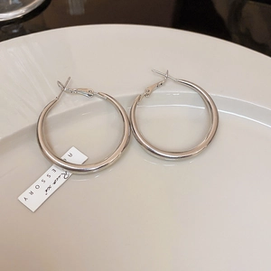 Macro shot of silver-colored large hoop earrings featuring a high-gloss metallic finish
