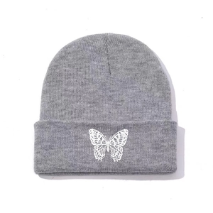 Close-up of a grey beanie showing white butterfly embroidery and knit texture