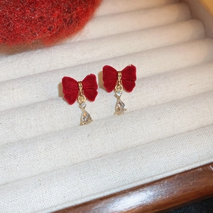 Détail de boucles d'oreilles nœud velours rouge avec cristaux de zircon en boîte