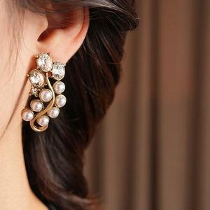 Detailed close-up of vintage gold earrings with crystals and pearls on a model