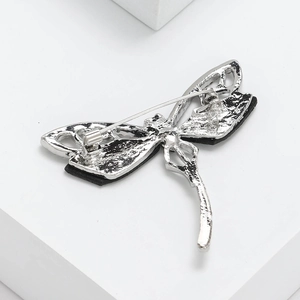Back view of silver dragonfly brooch with metal pin buckle on white pedestal stand