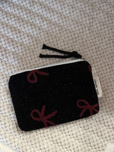 Macro shot of black knitted coin purse with red bow patterns and silver metal zipper detail