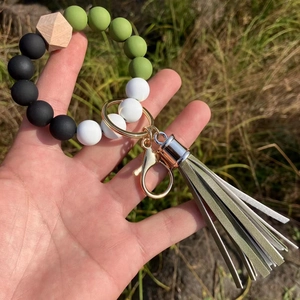 Close-up of silicone beaded keychain with wooden bead, golden ring and leather tassel
