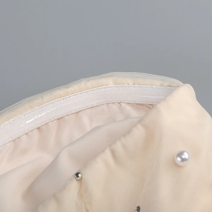 Dettaglio di tulle beige con decorazioni di perle e fodera in raso su abito da festa