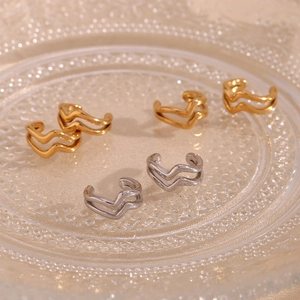 Detail of gold and silver double-layered wavy ear cuffs on a decorative glass tray