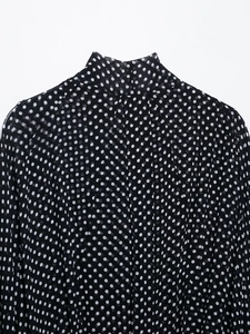 Detailed view of the high neck collar and polka dot pattern on the black chiffon blouse