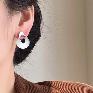 Close-up of a twisted silver-tone abstract earring with textured surface on a model