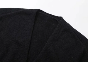 Close-up of the V-neckline and fine knitted texture of this black cardigan sweater