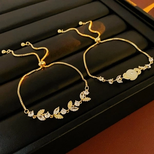 Dettaglio di braccialetti regolabili placcati oro con foglie, fiori e zirconi luminosi