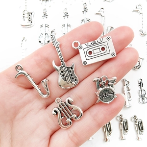 Silver musical instrument charms including guitar and saxophone held in hand