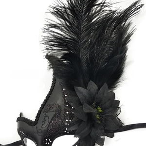 Dettaglio di una maschera nera per mascherata con piume delicate e decorazioni floreali