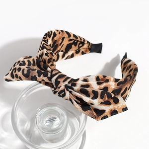 Detail of leopard print headband featuring a chic bow design on glass stand