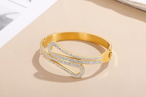 Close-up of golden stainless steel bangle with pavé rhinestones in a spiral design