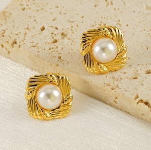 Macro view of vintage 18K gold earrings with large baroque pearls on textured stone