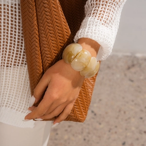Detail of amber resin stretch bracelet with marble texture worn by a model in soft light