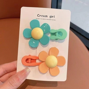 Close-up of set of two sweet floral hair clips in vibrant green and orange colors