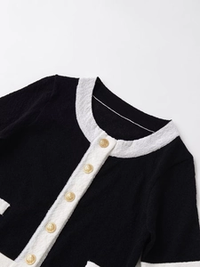 Close-up of contrast tweed jacket featuring white trim and embossed gold metal buttons