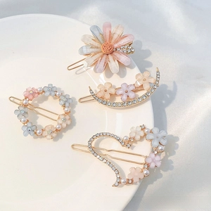 Macro view of four flower hair clips with rhinestones and pearls on a white porcelain plate