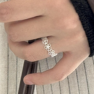 Detail shot of a silver hollow floral S925 sterling silver ring worn on a hand