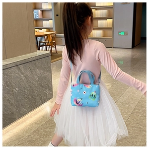 Blue canvas kids crossbody bag with cartoon monster prints shown on model back view