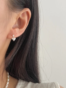 Close-up of minimalist S925 sterling silver heart-shaped drop earrings worn on ear