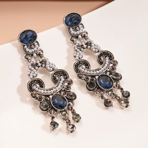 Detail view of vintage-style earrings with blue gemstones, pearls, and dark rhinestones