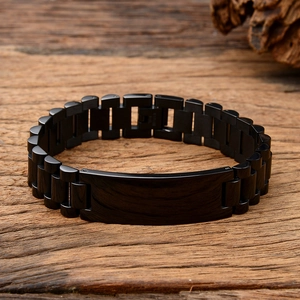 Detail of black stainless steel watch-band style bracelet on rustic wood background