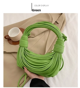Detail of green pleated knot handbag with unique leather woven texture on neutral background