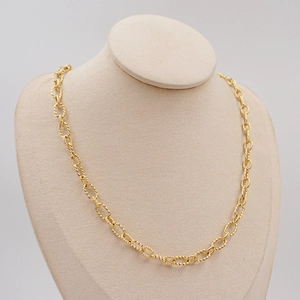 Polished gold twist chain necklace featuring textured oval links on a beige display stand