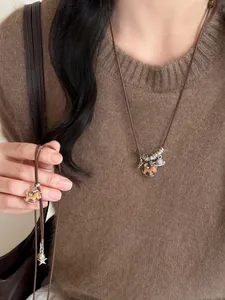 Détail d'un collier vintage avec pendentif cheval en bois et planète sur un pull en maille