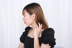 Side view of model wearing large golden heart-shaped stainless steel hoop earrings