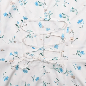 Detailed view of the elegant criss-cross lace-up back design on a floral satin midi dress