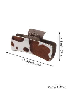 Macro view of large cow print hair claw clip showing 10.5cm length and matte brown resin