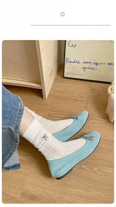 Close-up of light blue suede ballet flats with bow detail and white mesh crew socks