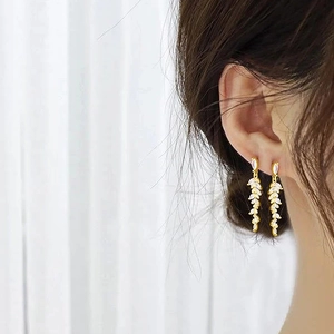 Elegant gold tassel earrings with leaf-shaped cubic zirconia worn by model in soft light