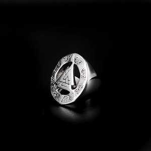 Close-up macro view of vintage stainless steel men's ring featuring engraved symbols