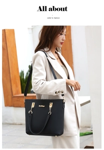 Street style view of a black leather tote bag worn by a model in a white blazer