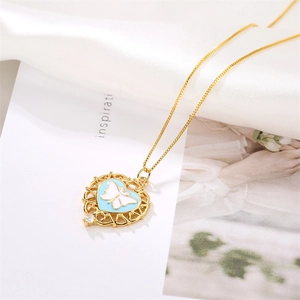 Detailed shot of a gold heart pendant with a blue butterfly and diamond on silk
