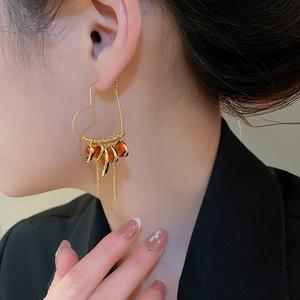 Detail of 18K gold plated heart earrings with amber crystals and long metal tassels