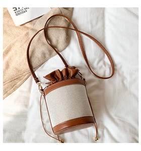Detail of canvas bucket bag with brown leather drawstring closure and golden hardware