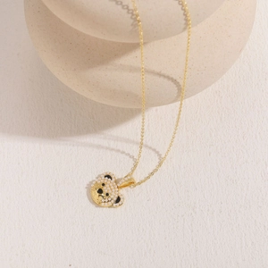 Close-up of golden bear pendant with white micro pearls and black enamel detailing