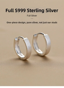 Macro shot of S999 fine silver matte brushed huggie earrings on textured fabric