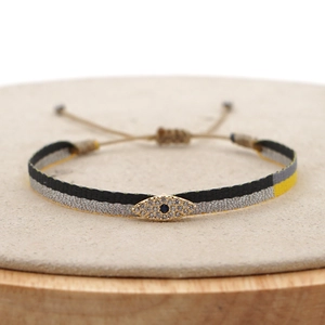 Detailed macro view of an adjustable woven evil eye bracelet with sparkling crystals