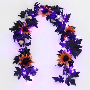 Detail of Halloween garland with black maple leaves, gold pumpkins and purple LED lights