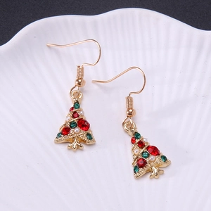 Detailed view of Christmas tree earrings with colorful rhinestones on a shell background